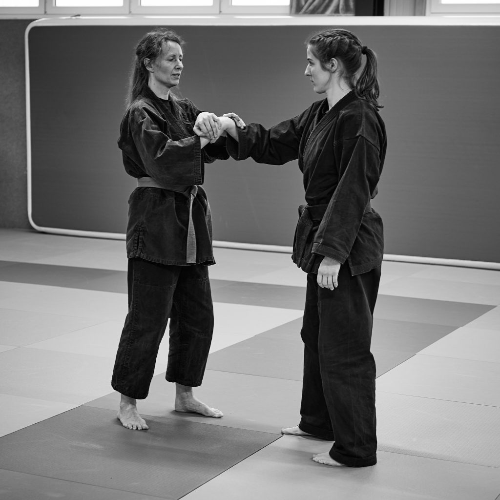 Judokämpfer mit Schwarzgurt zeigt Frauen Kniffe zur